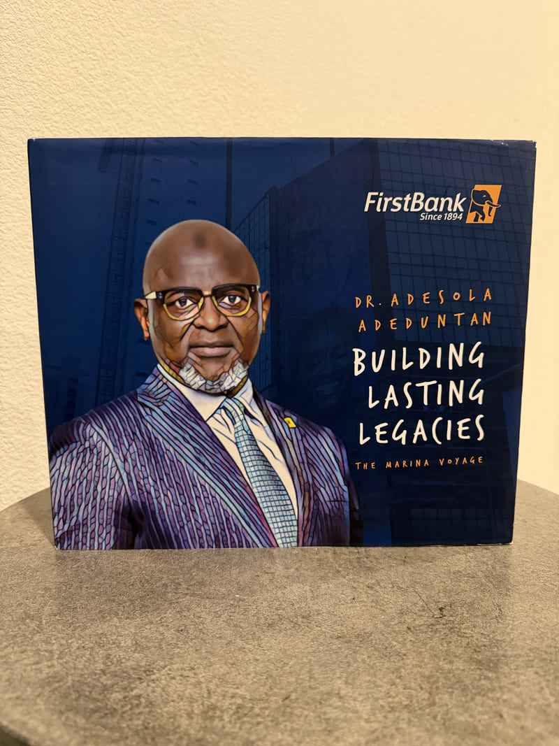FirstBank keepsake box titled Building Lasting Legacies, The Marina Voyage, with an illustrated portrait of Dr. Adesola Adeduntan.